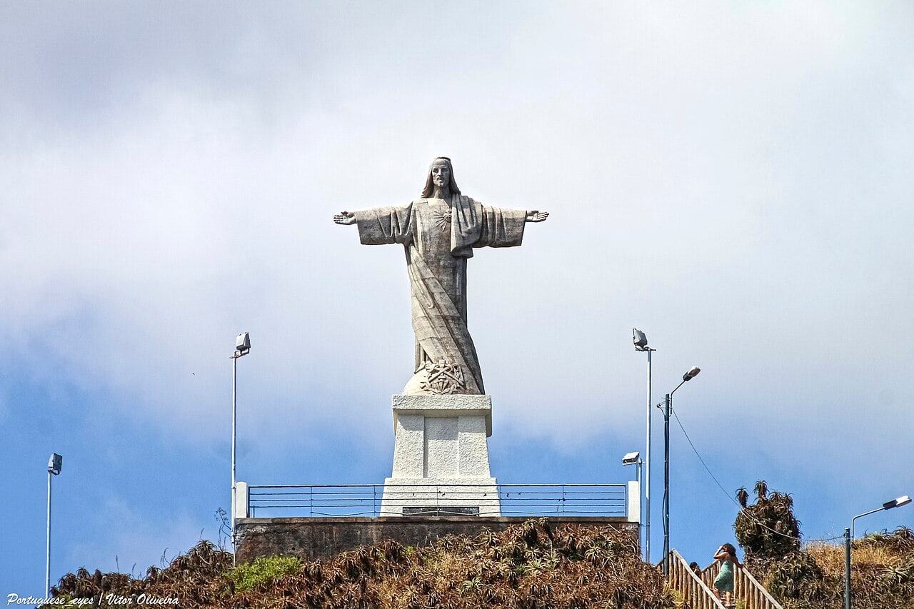 A estátua do Cristo Rei no Garajau, vista de frente com os braços abertos sobre o pedestal de pedra.