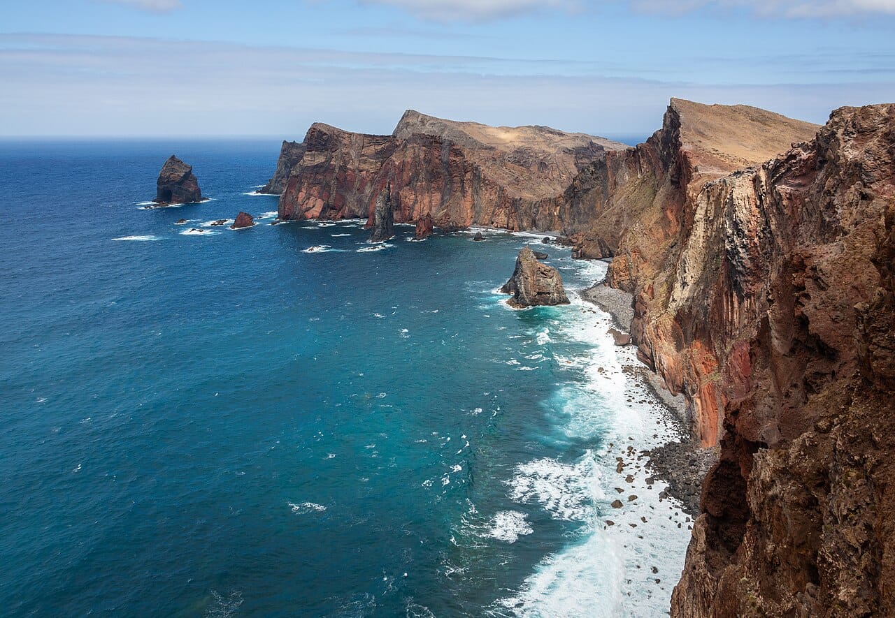 Red cliffs and blue water at Ponta de São Lourenço, the exposed coastal scenery of the peninsula walk.