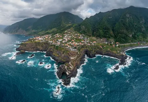 Seixal’s houses sit between steep green mountains and the sea, showing the coastal setting of the visit.